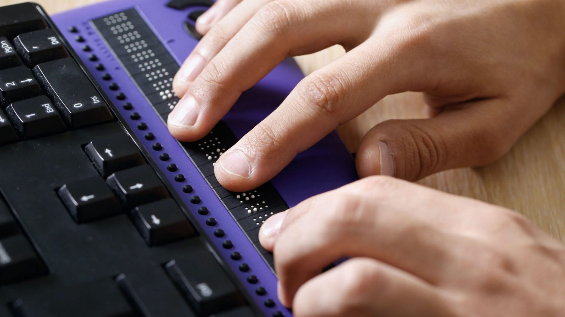 Blind person using computer with braille computer display and a computer keyboard, all compatible with EnhancedBallot.